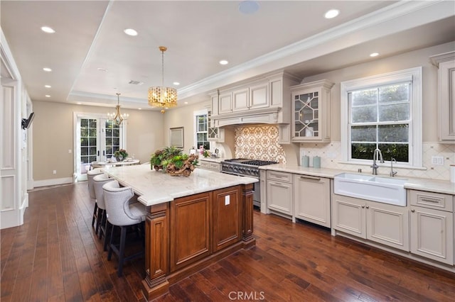 kitchen featuring pendant lighting, a center island, high end stove, paneled dishwasher, and a tray ceiling