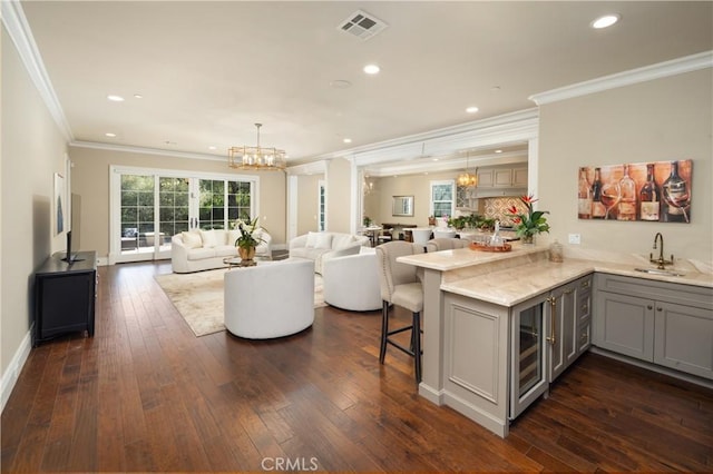 living room with dark hardwood / wood-style flooring, beverage cooler, a chandelier, crown molding, and sink