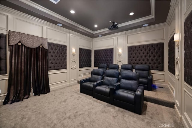 home theater room featuring light colored carpet, a tray ceiling, and ornamental molding