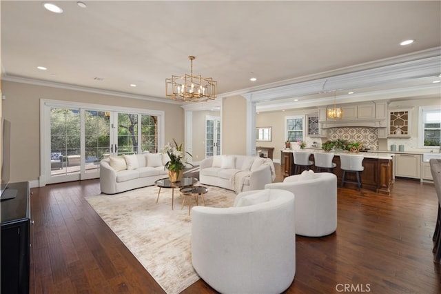 living room featuring an inviting chandelier, crown molding, and dark hardwood / wood-style floors