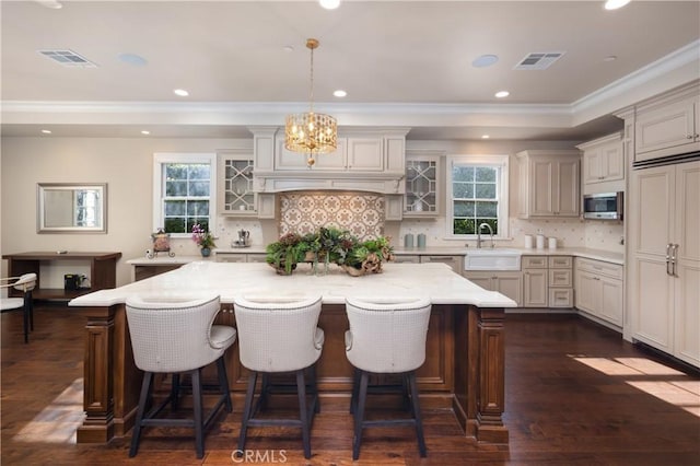 kitchen featuring a large island, a breakfast bar area, backsplash, decorative light fixtures, and dark hardwood / wood-style flooring