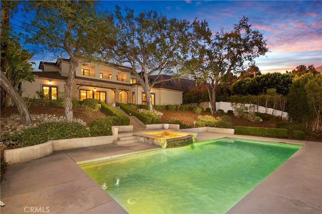 pool at dusk with an in ground hot tub