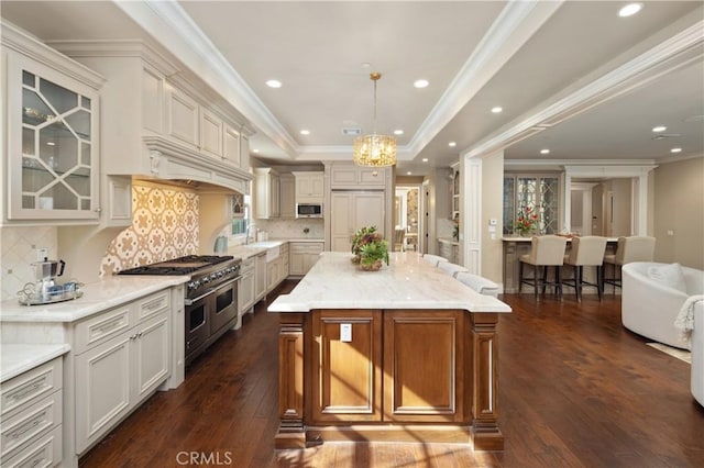 kitchen featuring a kitchen island, decorative backsplash, high end appliances, hanging light fixtures, and light stone countertops