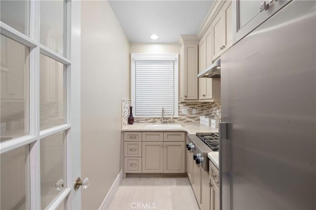 kitchen featuring light tile patterned floors, cream cabinetry, appliances with stainless steel finishes, tasteful backsplash, and sink