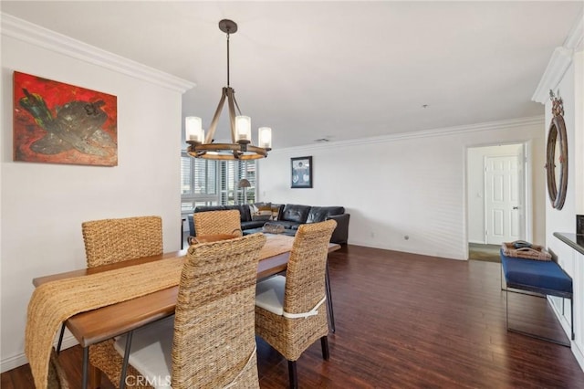 dining room with crown molding, dark wood finished floors, and an inviting chandelier