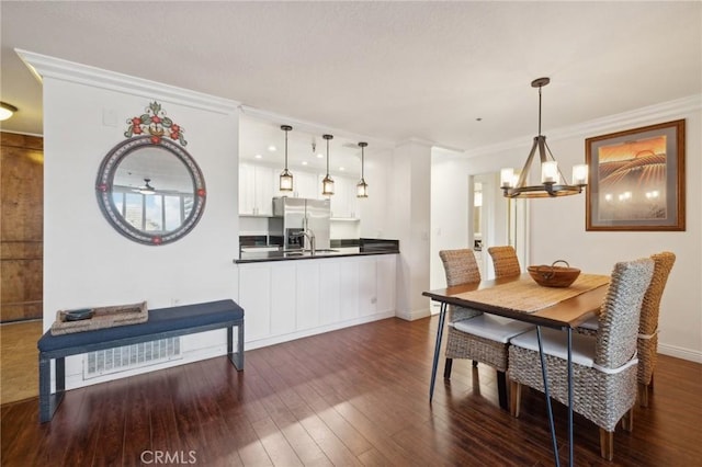 dining area with crown molding, dark hardwood / wood-style floors, a chandelier, and sink