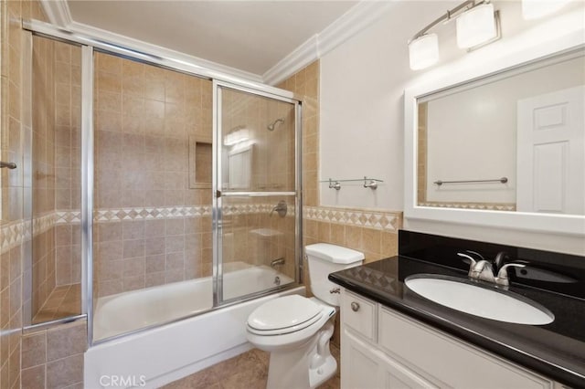 full bath featuring toilet, shower / bath combination with glass door, crown molding, vanity, and tile walls