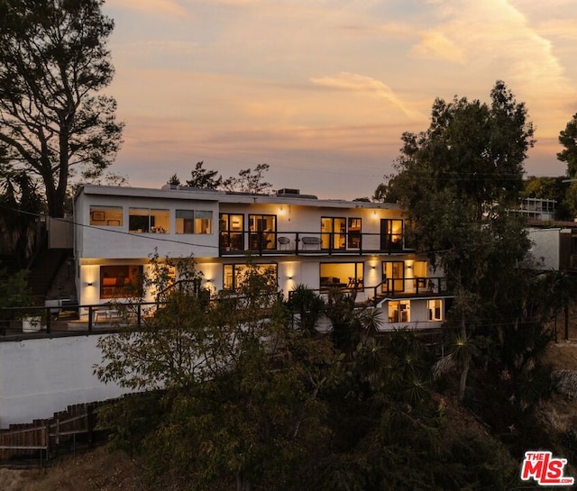 back house at dusk with a balcony