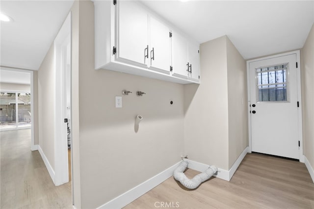 laundry area with plenty of natural light, cabinets, and light hardwood / wood-style floors