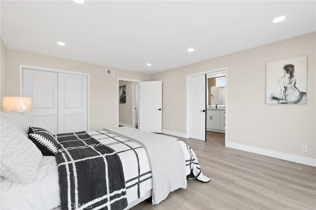 bedroom featuring ensuite bath, light hardwood / wood-style flooring, and a closet