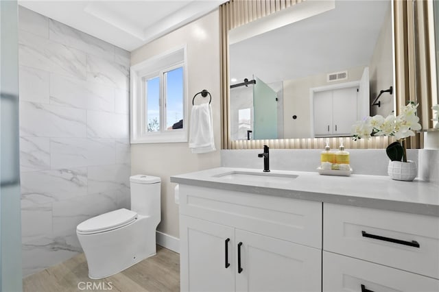 bathroom with hardwood / wood-style flooring, vanity, toilet, and a shower