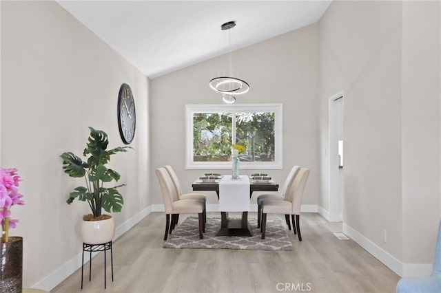 dining area with light hardwood / wood-style floors and high vaulted ceiling