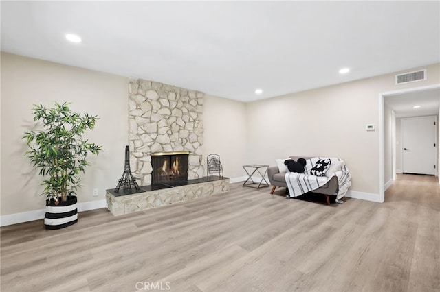 living room featuring a stone fireplace and light wood-type flooring