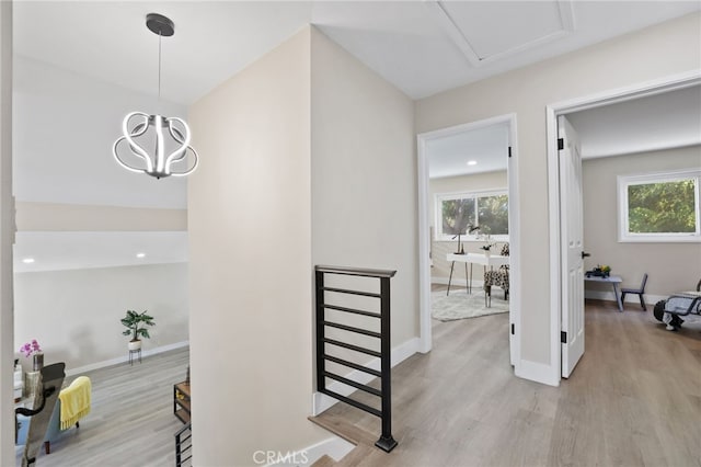 hall with plenty of natural light, light hardwood / wood-style floors, and a chandelier