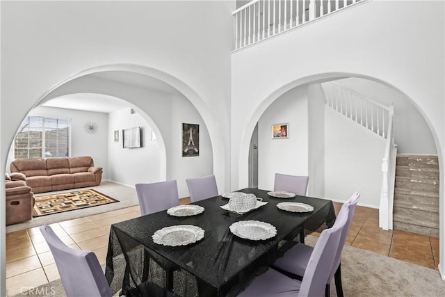 dining room with a towering ceiling and light tile patterned floors