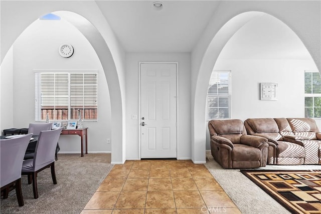 foyer featuring plenty of natural light, light tile patterned floors, and lofted ceiling