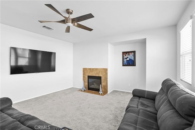 carpeted living room featuring ceiling fan and a tiled fireplace