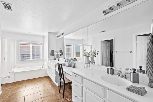 bathroom featuring vanity, a bath, a textured ceiling, and tile patterned floors