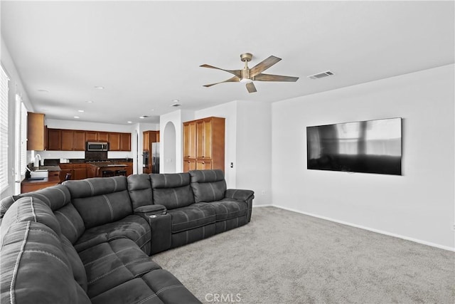 living room with ceiling fan, sink, and light carpet