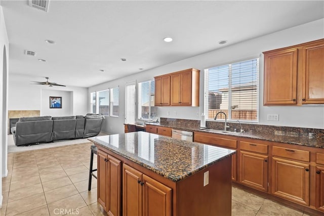 kitchen featuring dishwasher, sink, a kitchen island, and a healthy amount of sunlight