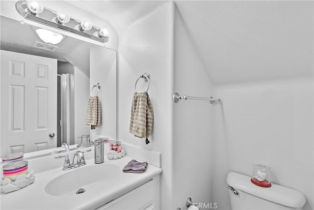 bathroom featuring toilet, vanity, and vaulted ceiling