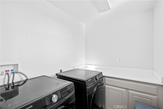 laundry room with separate washer and dryer and cabinets