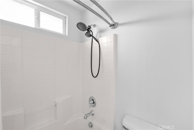 bathroom with toilet and tiled shower / bath