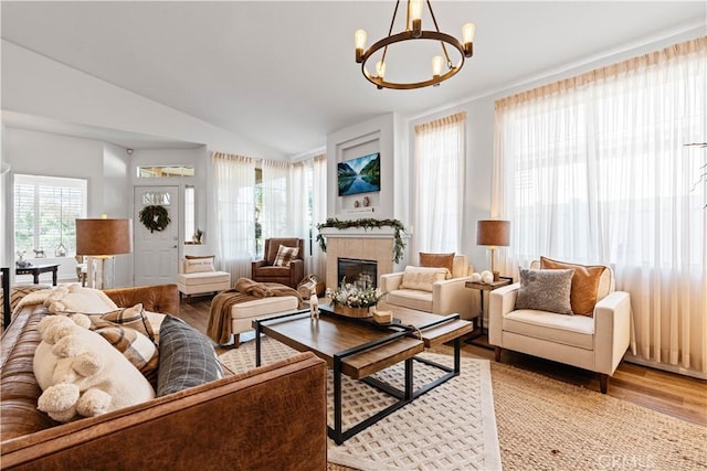 living room with a fireplace, an inviting chandelier, hardwood / wood-style flooring, and vaulted ceiling