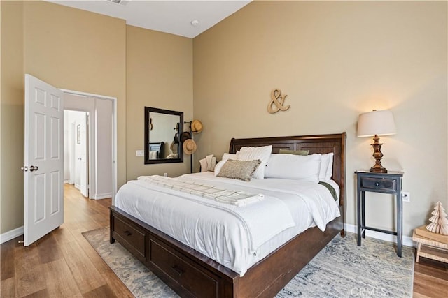 bedroom featuring wood-type flooring and a high ceiling