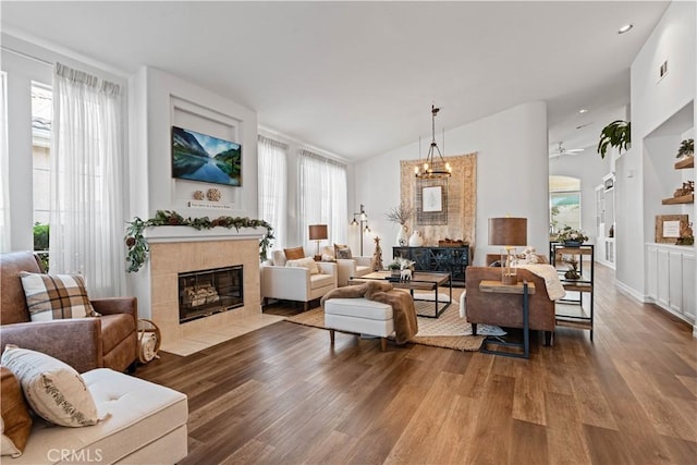 living room with a tiled fireplace, a wealth of natural light, hardwood / wood-style floors, and lofted ceiling