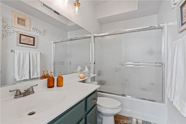 full bathroom featuring vanity, toilet, and bath / shower combo with glass door