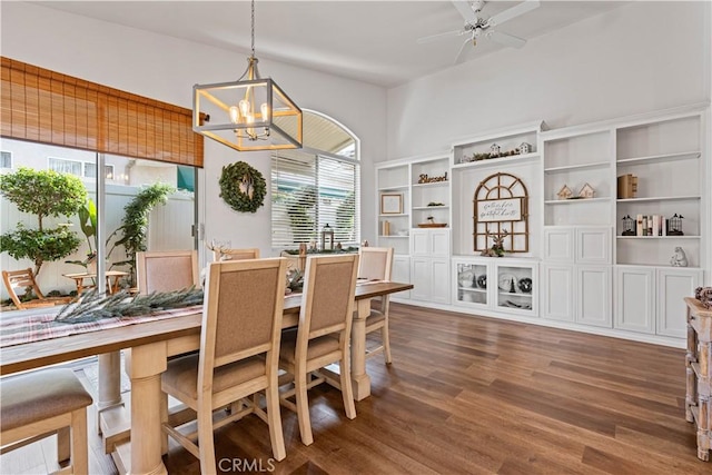 dining area with ceiling fan with notable chandelier and dark wood-type flooring