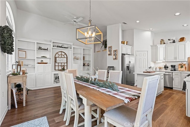 dining space with ceiling fan with notable chandelier and dark hardwood / wood-style flooring