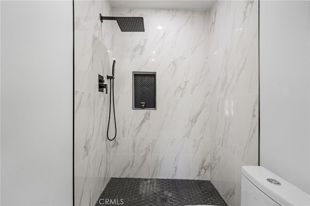 bathroom with a tile shower and toilet