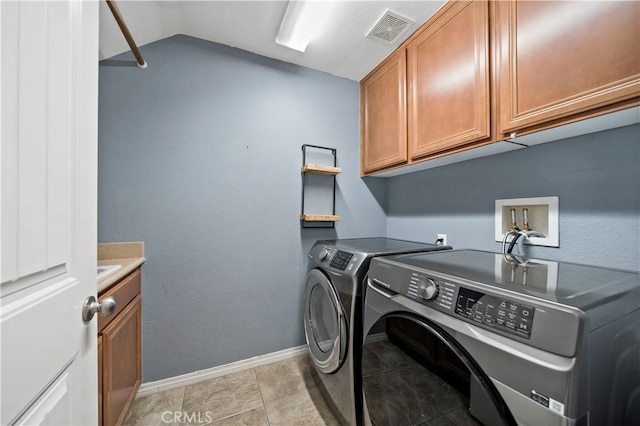 clothes washing area with cabinets, separate washer and dryer, and light tile patterned floors