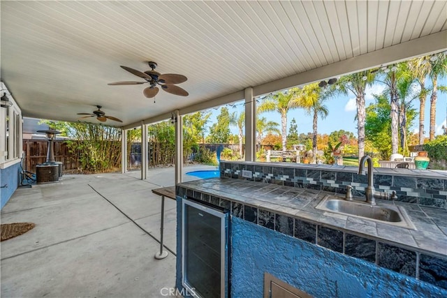 view of patio with ceiling fan, sink, and beverage cooler