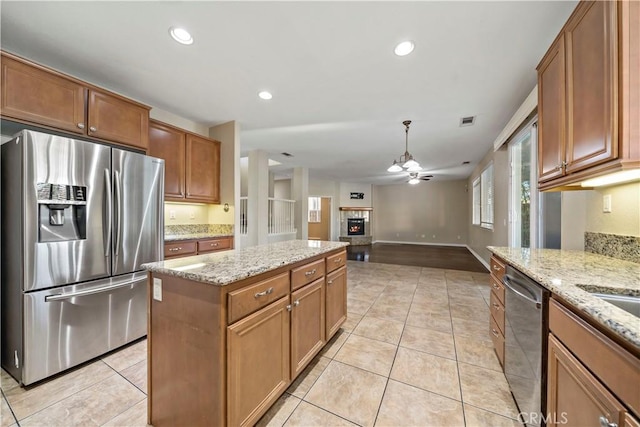 kitchen with light tile patterned floors, appliances with stainless steel finishes, and light stone countertops