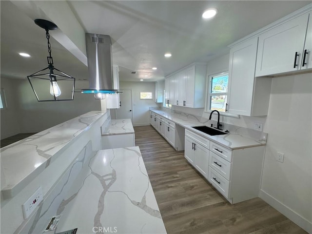 kitchen with sink, island range hood, white cabinetry, and pendant lighting