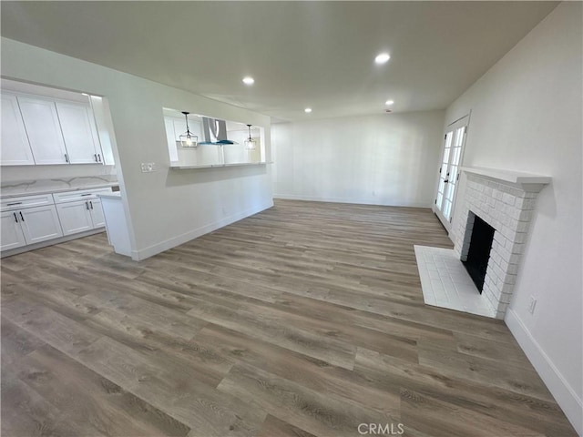 unfurnished living room featuring a brick fireplace and wood-type flooring