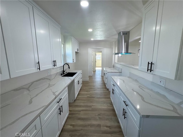 kitchen with light stone countertops, island range hood, white cabinets, and sink