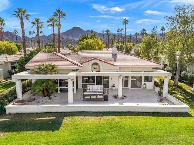 rear view of property featuring a lawn, an outdoor living space, and a mountain view