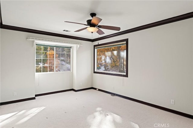 spare room with ceiling fan, crown molding, and light carpet