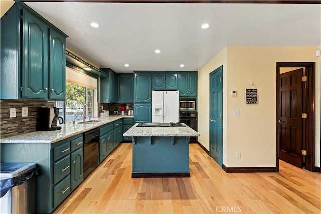 kitchen with light wood-type flooring, backsplash, sink, black appliances, and a kitchen island