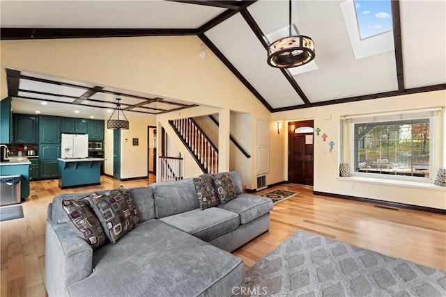 living room with light hardwood / wood-style floors, beam ceiling, high vaulted ceiling, and a skylight