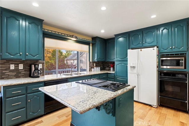 kitchen with decorative backsplash, light wood-type flooring, sink, black appliances, and a center island