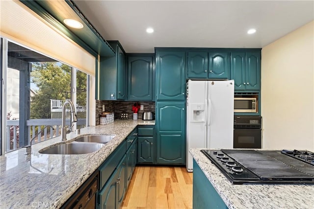 kitchen featuring sink, light stone counters, light hardwood / wood-style flooring, backsplash, and black appliances