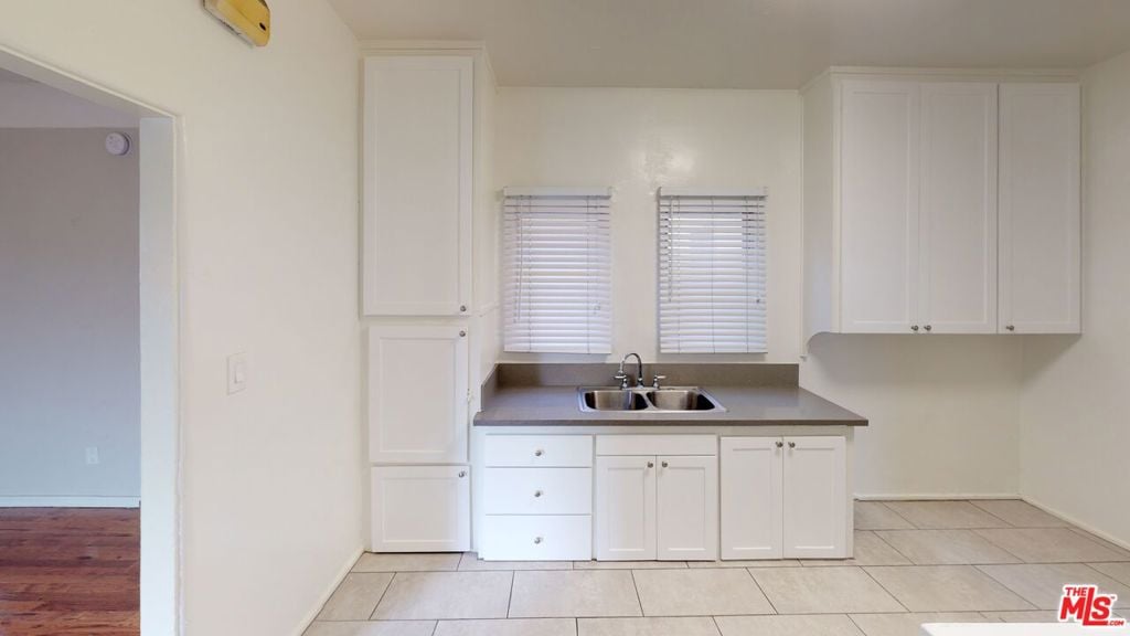 kitchen with light tile patterned flooring, white cabinetry, and sink