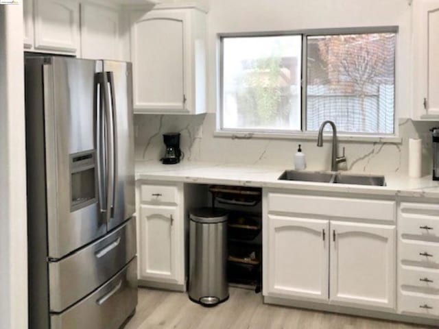 kitchen featuring white cabinetry, stainless steel fridge with ice dispenser, sink, and a wealth of natural light