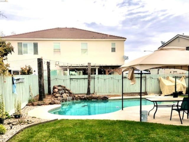 back of property featuring a yard, a fenced in pool, and a patio