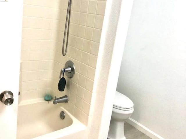 bathroom featuring tiled shower / bath and toilet